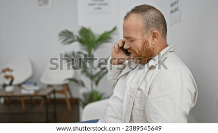 Cheerful middle-aged caucasian man having a lively chat on his smartphone whilst sitting comfortably in the waiting room, radiating happiness all around.