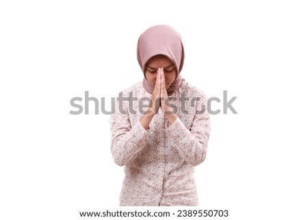Grateful Young asian muslim girl standing while praying. Isolated on white