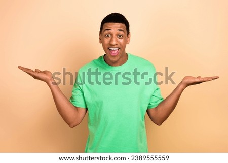 Photo portrait of attractive young man excited hands balance scales wear trendy green clothes isolated on beige color background