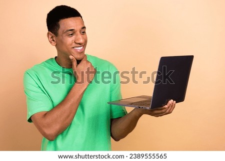 Photo portrait of nice young male touch chin working minded netbook dressed stylish green outfit isolated on beige color background