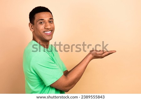Photo portrait of attractive young man palms hold empty space dressed stylish green clothes isolated on beige color background