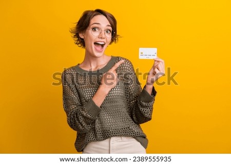 Photo portrait of attractive young woman hold point credit card wear trendy knitwear khaki clothes isolated on yellow color background