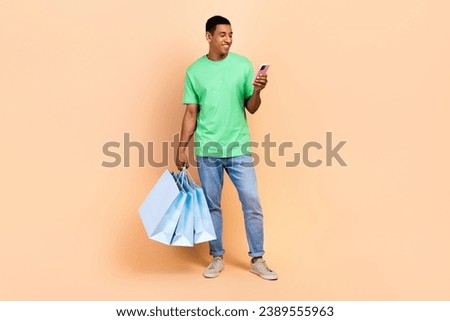 Full size photo of intelligent guy dressed green t-shirt pants look at smartphone order new outfit isolated on beige color background