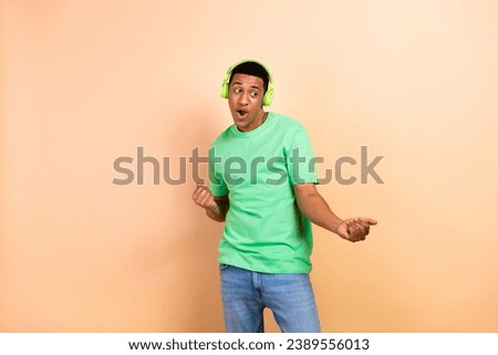 Photo portrait of attractive young man dancing have fun earphones dressed stylish green clothes isolated on beige color background
