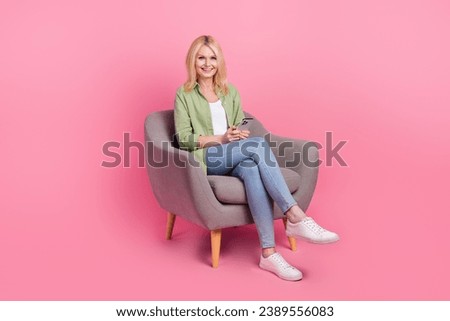 Full size photo of attractive positive lady sitting comfort chair use smart phone isolated on pink color background