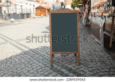 Wooden rustic blackboard in front of restaurant entrance. Mock up menu blank blackboard sign stand shop cafe restaurant. High quality photo