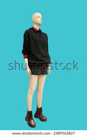 Full length image of a female display mannequin wearing black hoodie with kangaroo pocket isolated on a blue background