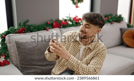 Young arab man make photo to christmas tree at home