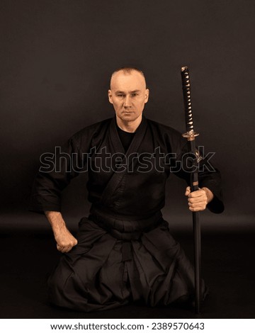 Portrait of aikido sensei master with black sensei belt in taekwondo kimono witn sword katana on black background. Traditional samurai hakama kimono. Healthy lifestyle and sports concept. Royalty-Free Stock Photo #2389570643