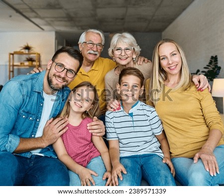Portrait of a three generation famili, grandparents, parents and children sitting on sofa and having fun posing at home Royalty-Free Stock Photo #2389571339