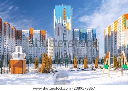 View of the building in an economy class residential complex with landscaping and a playground . Residential architecture in the winter season .  Royalty-Free Stock Photo #2389573867