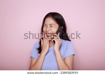 Asian woman cheerfully posing with a mobile, A beautiful young woman is feeling cheerful and happy., half body photo of nice positive lady, Portrait of a beautiful young woman in light pink background