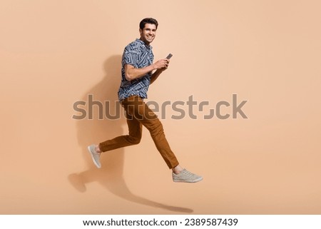 Full length size photo of rushing going guy with smartphone browsing internet when being late for job isolated on beige color background