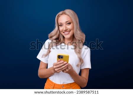 Photo of cute adorable girl dressed white trendy clothes hold phone samsung iphone isolated on dark blue color background