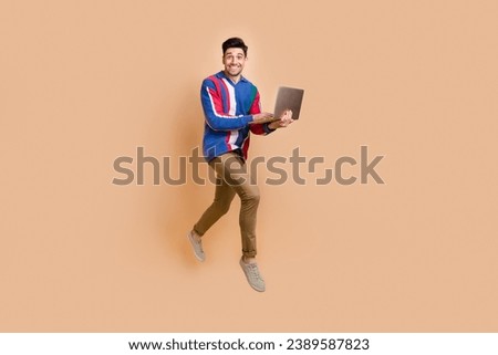 Full length photo of programmer running in air with his modern laptop to buy things with huge discounts isolated on beige color background