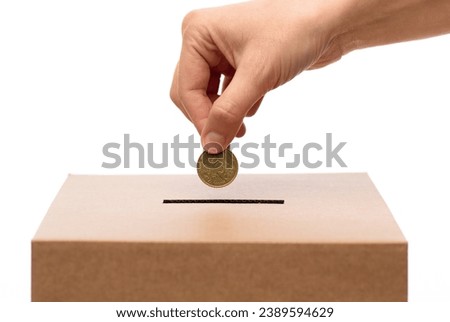 charity, savings and fundraising concept - close up of hand putting coin into donation box