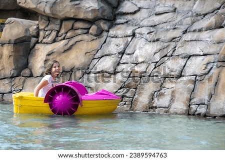 a small handsome curly boy is engaged in sports, the boy is engaged in rafting, the child with a paddle on a raft or a catamaran. High quality photo