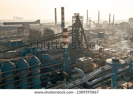 A sprawling industrial complex with several smokestacks and exhaust pipes emitting plumes of smoke into the air Royalty-Free Stock Photo #2389595867