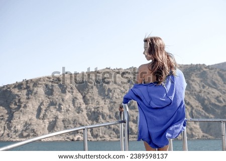 A beautiful girl with a slender figure travels and rests on a boat during a summer vacation in the open sea or ocean against the background of the island. A model is wearing a shurt and shirt