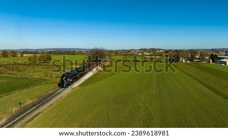 An Aerial View of a Streamlined Steam Passenger Train Traveling Thru Fertile Farmlands on an Autumn Day Royalty-Free Stock Photo #2389618981