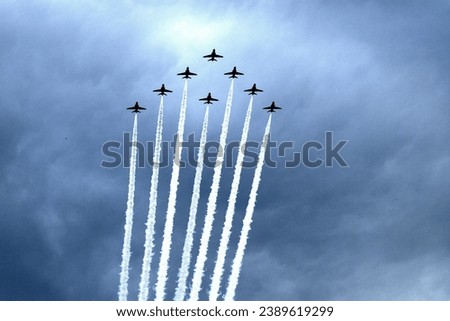 A picture of several airplanes in formation soaring through the sky, with white, billowing smoke trails trailing behind each one Royalty-Free Stock Photo #2389619299