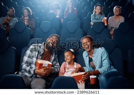 Happy African American family enjoying in movie projection in cinema. Copy space.