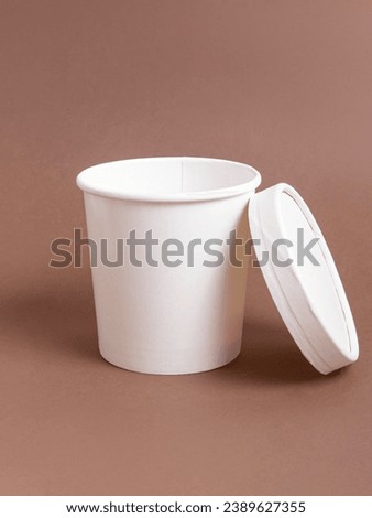 White disposable soup tureen with a lid on brown background. Disposable eco tableware. Cardboard soup tureen. Vertical Royalty-Free Stock Photo #2389627355