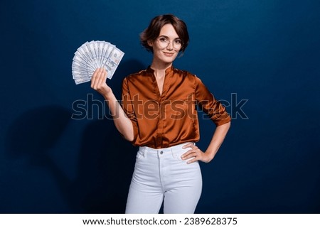 Photo portrait of pretty young girl hold money banknotes fan dressed stylish brown blouse isolated on dark brown color background