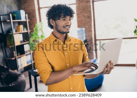 Photo portrait of handsome young guy wear yellow shirt hold netbook working remotely stylish room interior home office design