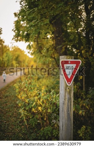 Yield sign outside in nature next to a bike path.