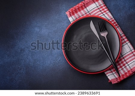 Round empty colored ceramic plate on concrete texture background. Preparing dishes and cutlery for dinner