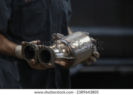 auto mechanic holding catalytic converter in auto repair shop Royalty-Free Stock Photo #2389643805