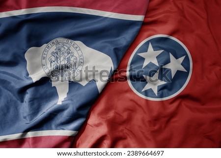 big waving colorful national flag of tennessee state and flag of wyoming state . macro
