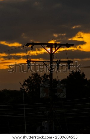 Silhouette of high voltage electric pole with sunset sky background.