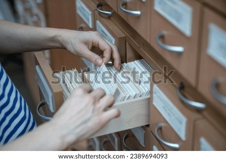 Woman finding book cars in university cards index catalog in library. Student goes through cards and looks for right one. Education in college, school, searching literature for study, learn concept.