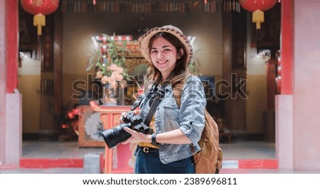 Young female traveler taking pictures at Chinese temple Young Asian woman in blue jacket using camera or phone Take cheerful pictures of Chinese temples or selfies.