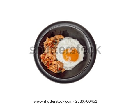 In the picture is a black plate with white cooked rice with stir-fried chicken and a fried egg. It is a very delicious Thai food.