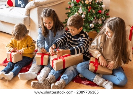Excited Children Unwrapping Christmas Gifts at Home