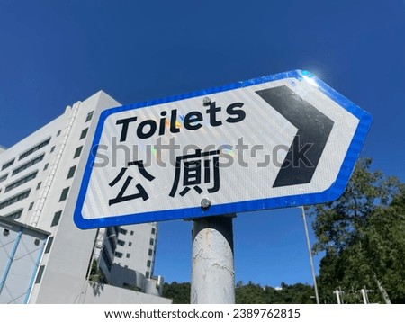 Angl photo of a toilet sign board on a post in teh street for people to know what way is the public toilets restroom WC water closet 