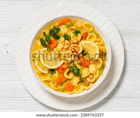 orecchiette veggies chickpea soup in white bowl on white wooden table, horizontal view from above, flat lay, close-up