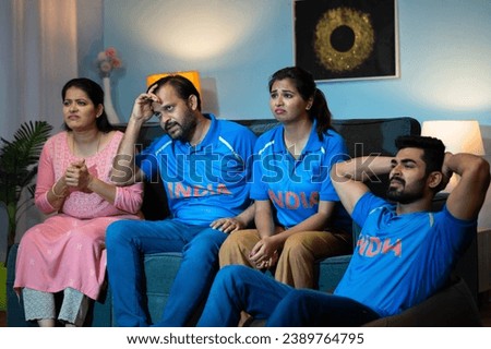 Indian Family with siblings got sad due to loss while watching cricket sports match at home on tv or television - concept of Disappointed Fans, Emotional reaction and Family bonding