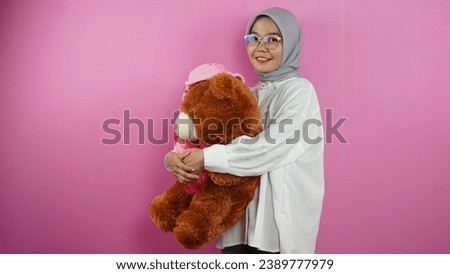 Muslim woman is carrying a teddy bear