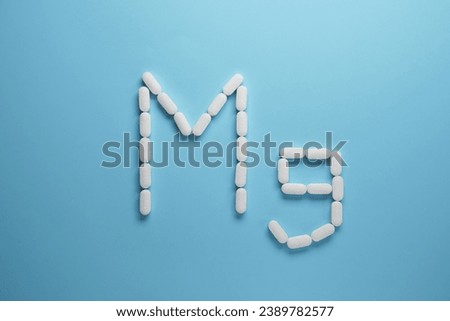 Mg element made of pills on blue background. Top view, flat lay.  Royalty-Free Stock Photo #2389782577