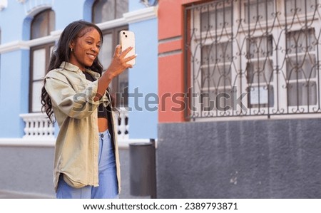 Young African woman using her phone on street in city of Tenerife Spain.