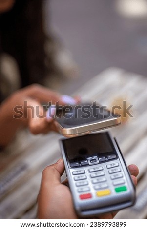 young woman with NFC technology in contactless payment terminal using her smartphone.