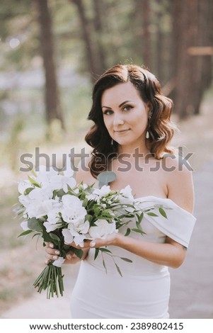 Wedding. A girl in a white dress holds in her hands a beautiful bouquet of white flowers and greenery