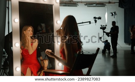 The actress is preparing to film a movie. She sits in front of a mirror on the set and applies makeup to herself. Backstage concept Royalty-Free Stock Photo #2389827083