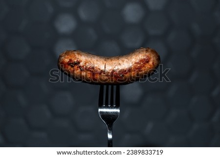 fried sausage on a fork on a dark background. food photo
