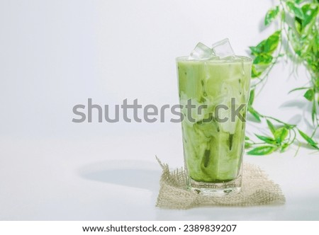 Homemade ice matcha latte green tea. a glass of white and green creamy cold drink of milk and matcha green tea isolated on white with bamboo leafs as background, copy space. 