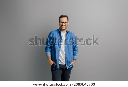 Portrait of handsome smiling entrepreneur with hands in pockets standing against white background